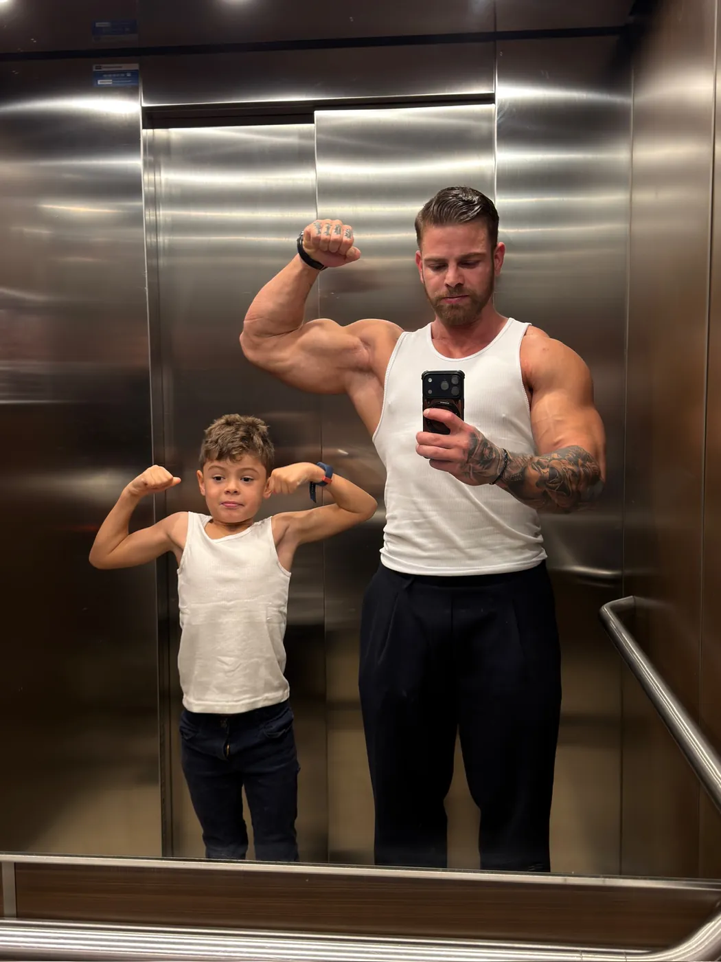 Arthur con su hijo, ambos flexionando el brazo frente a un espejo